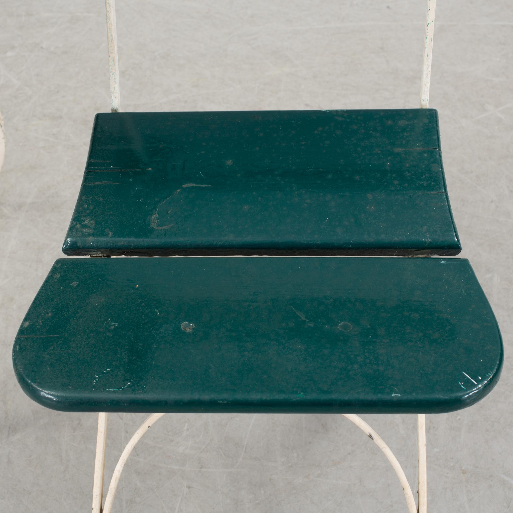 A pair of cast iron chais with wooden seats and a cast iron table, early 20th century.