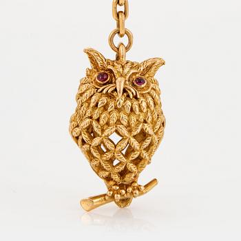 An 18K gold Hermès key chain in the form of an owl set with rubies.