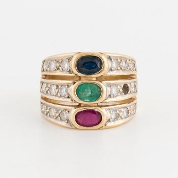 An oval cut ruby, sapphire and emerald ring, surrounded by brilliant cut diamonds.
