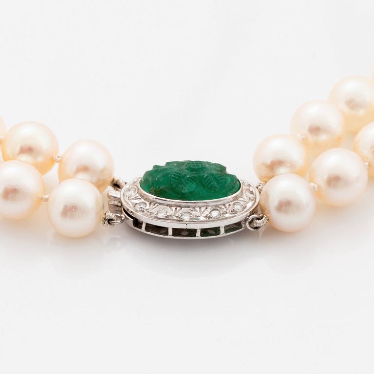 A two strand cultured pearl necklace with an 18K white gold and emerald clasp.