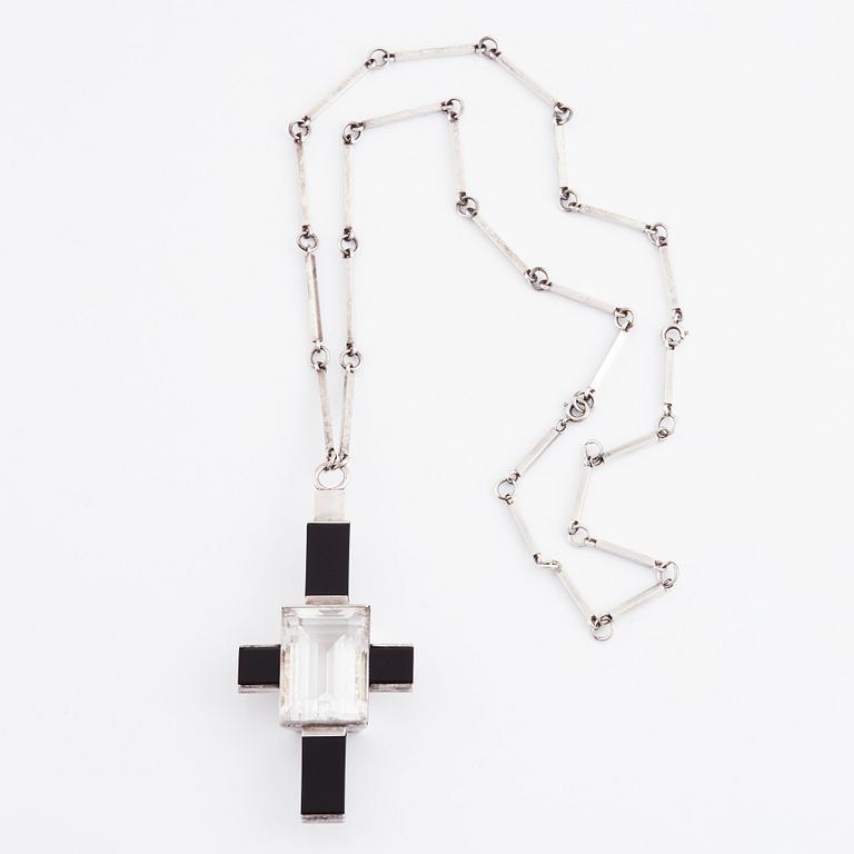 Wiwen Nilsson, hängsmycke i form av ett kors i sterlingsilver med fasettslipad bergkristall och onyx, Lund 1938.