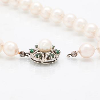A cultured pearl necklace with a lock in 18K white gold with green stones.