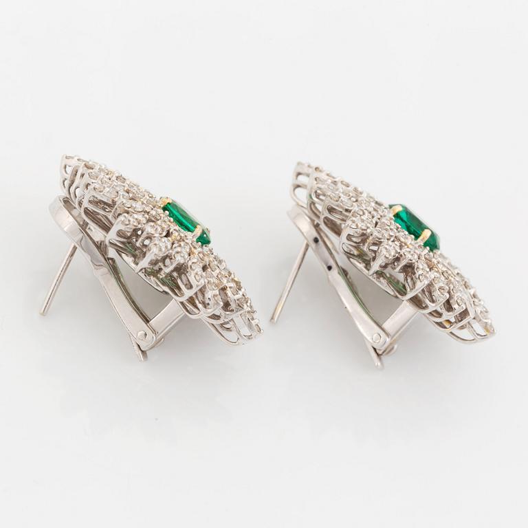 A pair of 18K white gold earrings set with faceted emeralds.