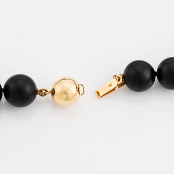 An onyx necklace, a pair of 18K gold earrings with two pairs of pendants in onyx and wood.