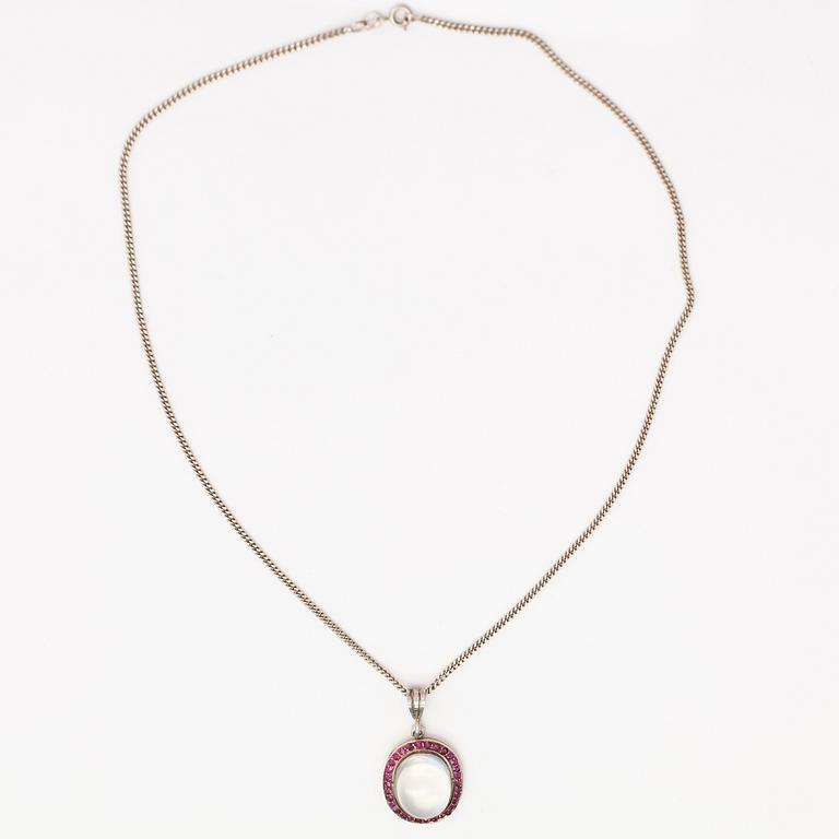 A 14K gold and silver necklace with a moon stone, rubies and a red glass stone.