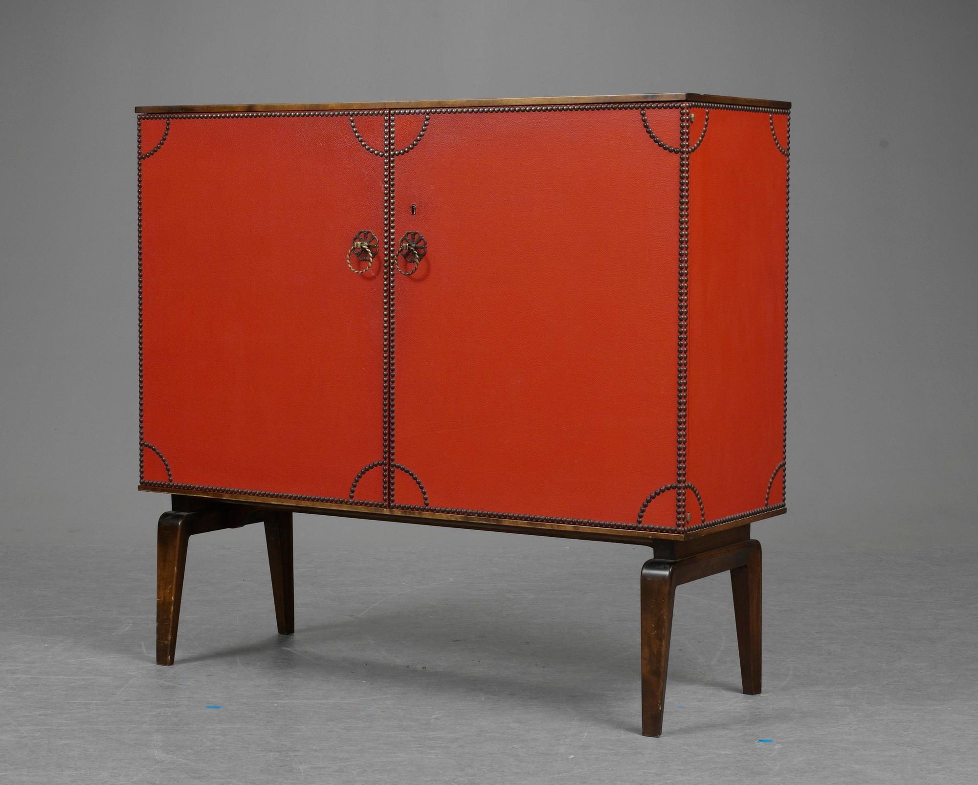 An Otto Schulz cabinet on stand with artificial red leather and brass details on a stained oak and birch stand, by Boet, Gothenburg, probably 1950's.
