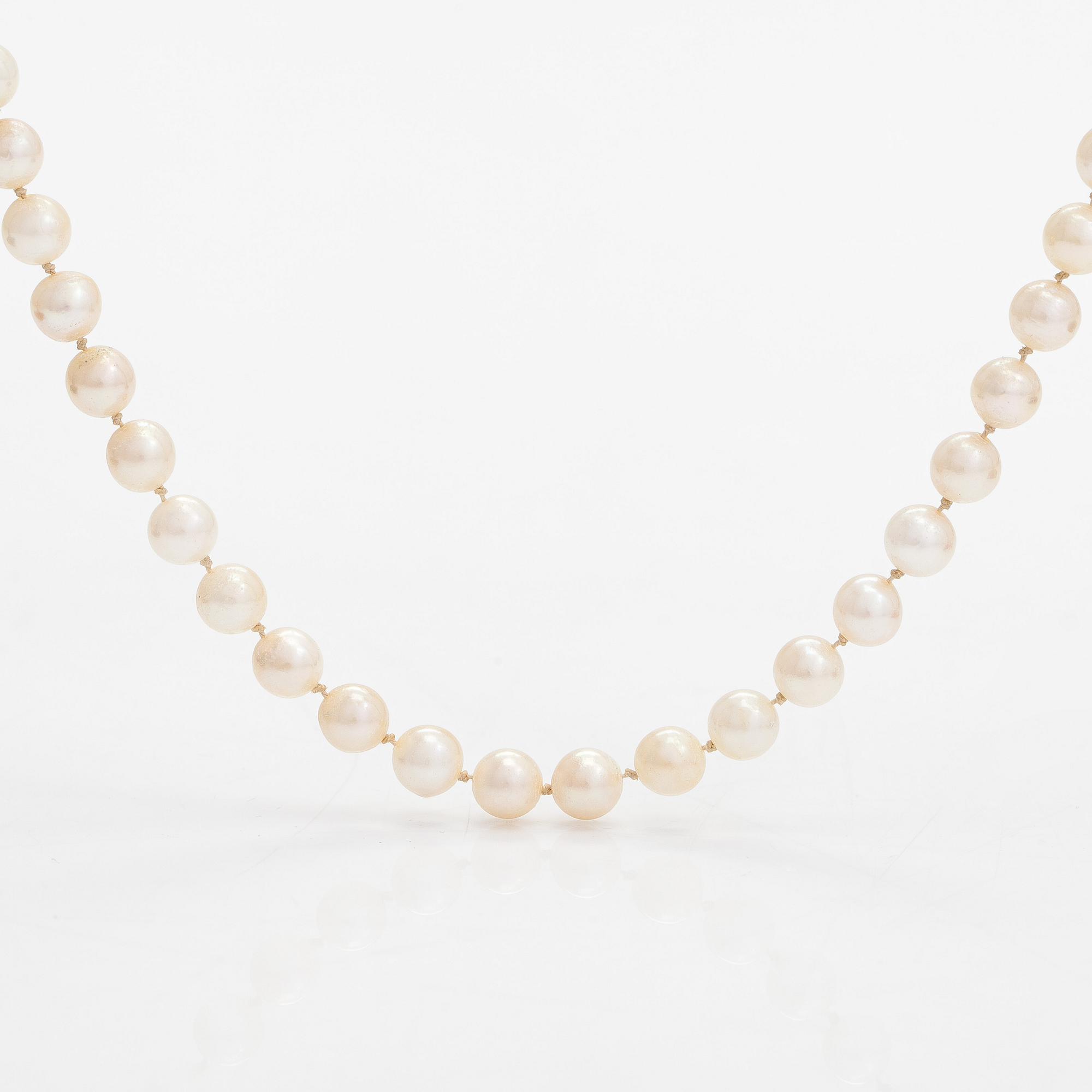 A cultured pearl necklace, clasp 18K gold with emerald and small diamonds.