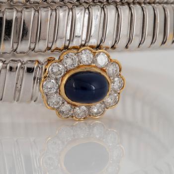 An 18K gold bangle set with cabochon-cut sapphires and round brilliant-cut diamonds.