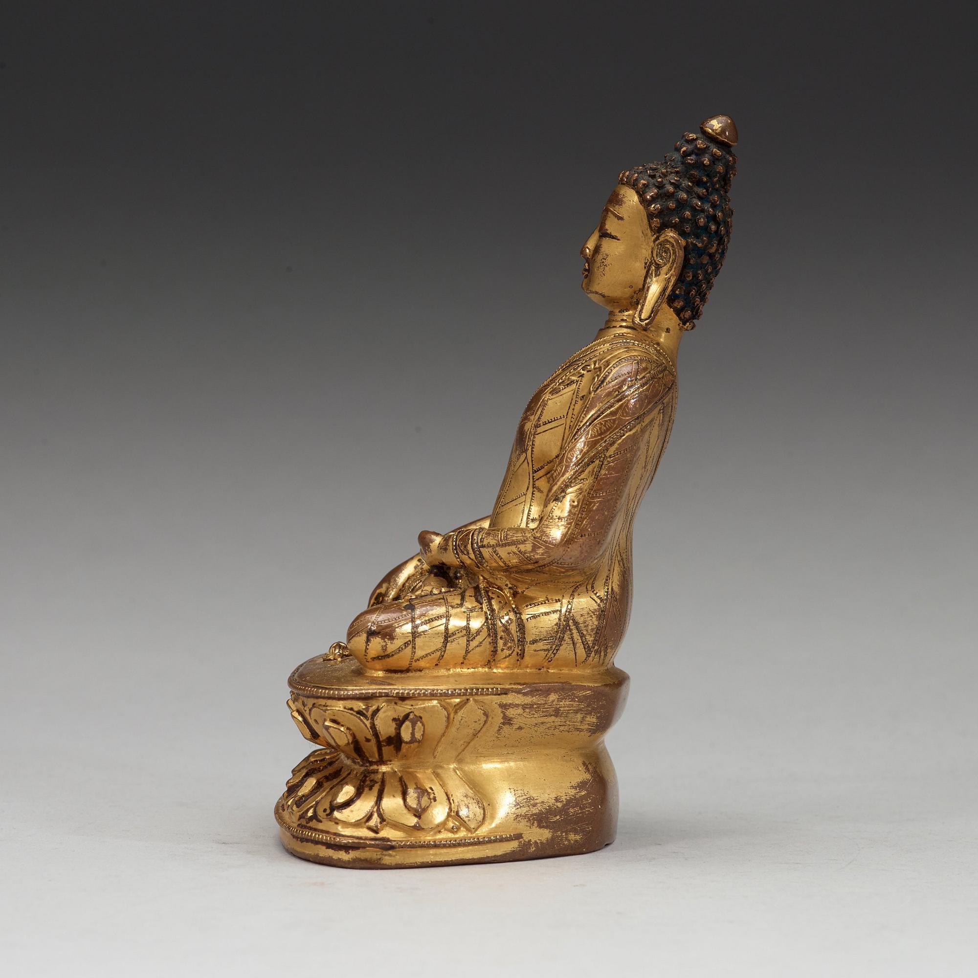 A gilt copper-alloy figure of Aksobhya Buddha, 15th/16th century, Tibet or Nepal.