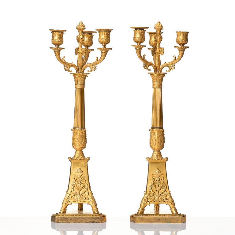 A pair of French Empire three-branch ormolu candelabra, early 19th century.