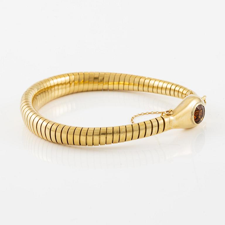 A bracelet in the shape of a serpent in 18K gold with a faceted citrine and rose-cut diamonds.
