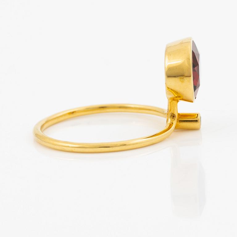 Ring in 18K gold with an oval faceted garnet and a brilliant-cut diamond.