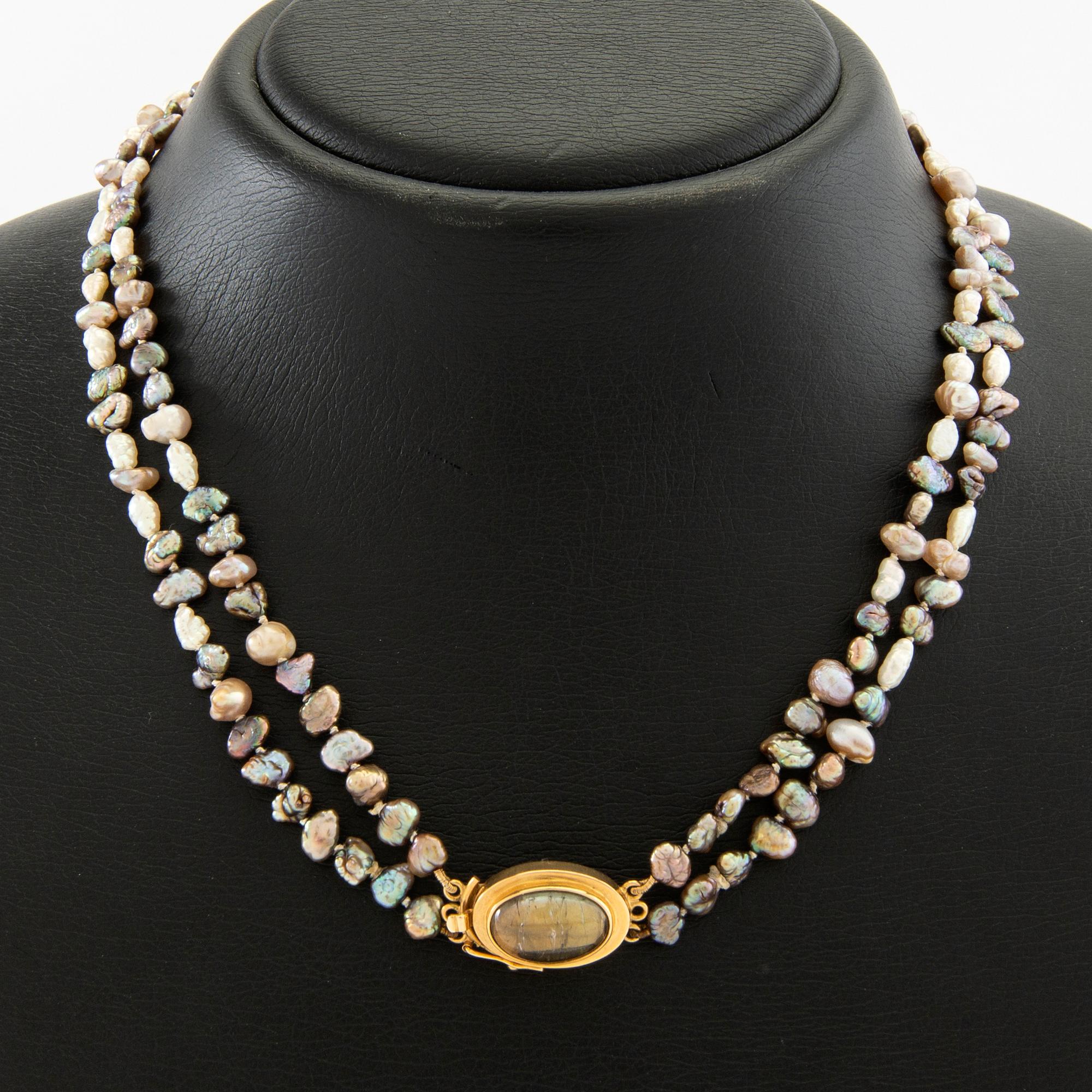 Necklace of cultured pearls with a clasp of 18K gold and cabochon-cut likely tourmaline.