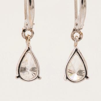 A pair of 18K white gold earrings set with pear cut diamonds.