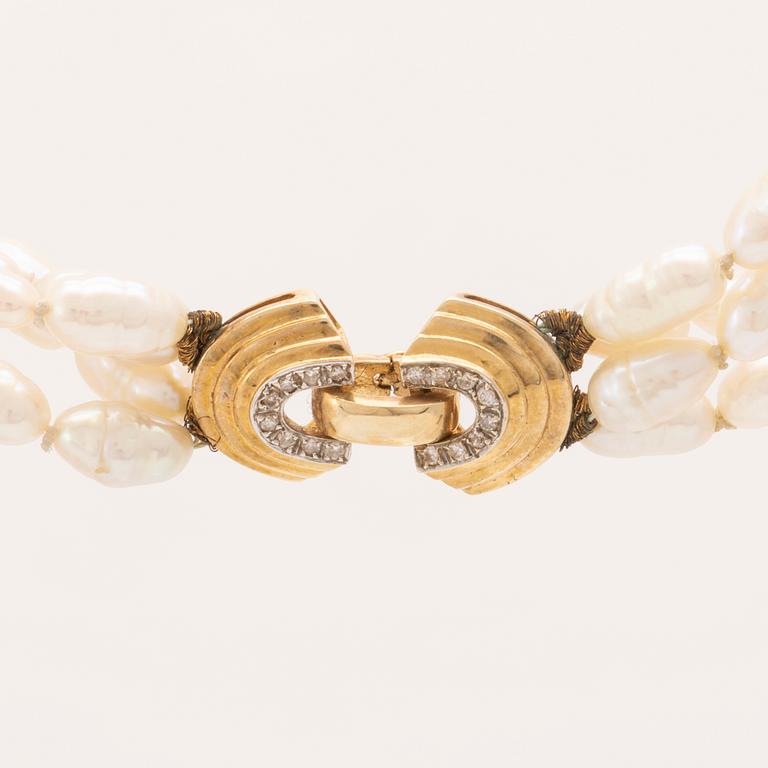 A necklace of cultured pearls set with a 14K gold lock and round brilliant cut diamonds.