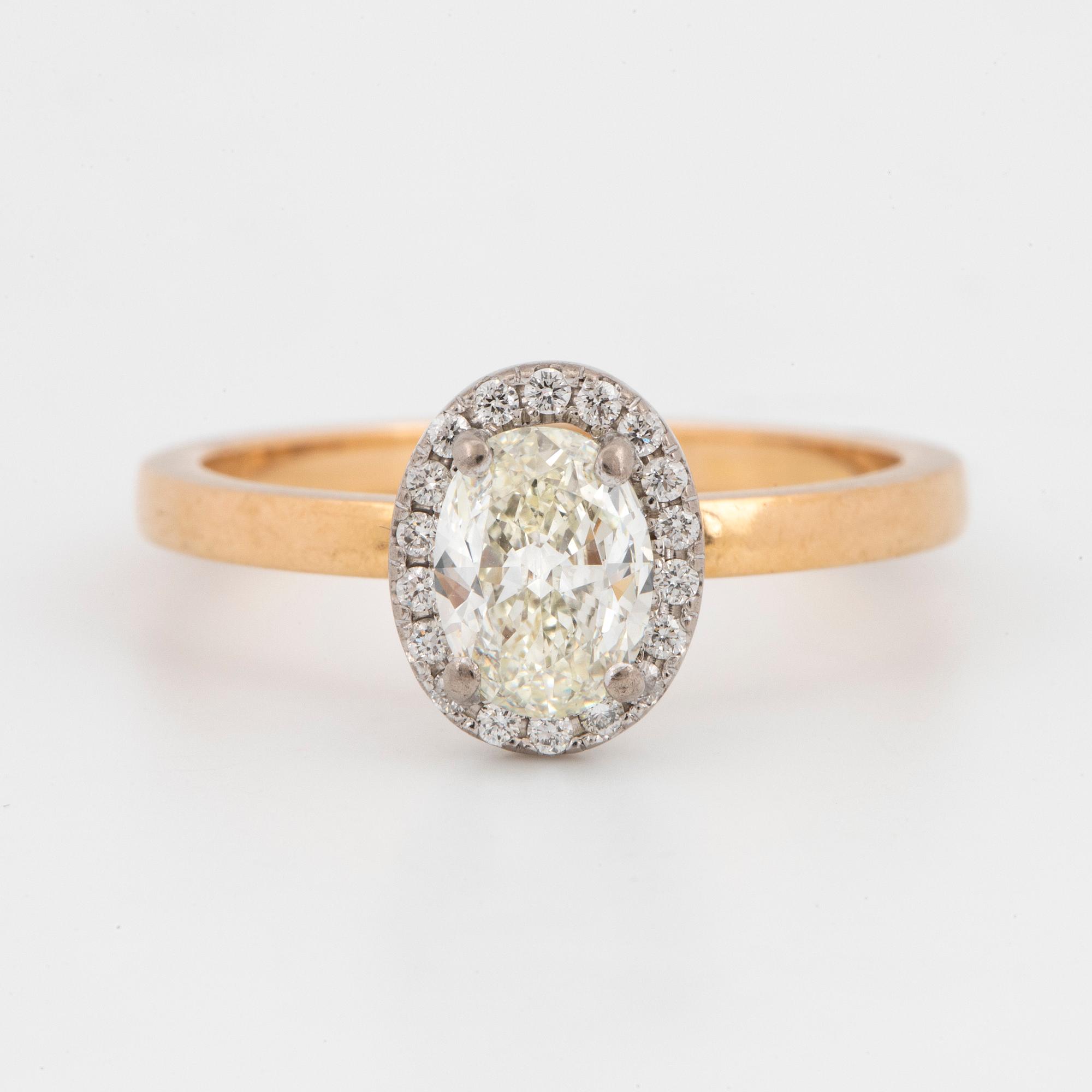 An 18k gold ring set with an oval brilliant-cut diamond.
