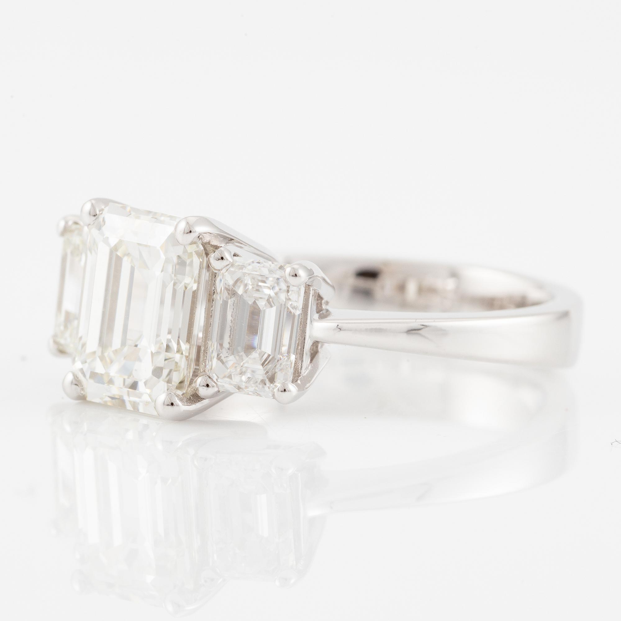 An 18K white gold ring set with three emerald-cut diamonds.