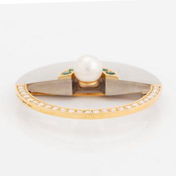 An 18K gold and white gold brooch set with a cultured pearl, round brilliant-cut diamonds and emeralds.