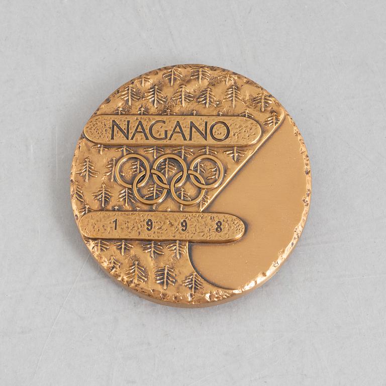Deltagarmedalj OS Nagano 1998 samt ett tygmärke för den Svenska OS-truppen.