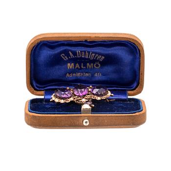 An 8K gold brooch set with seed pearls and faceted amethysts.