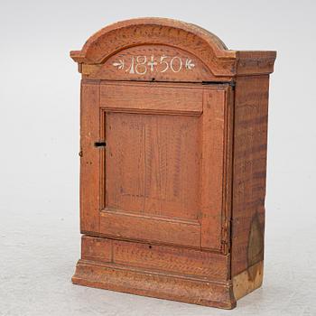 A hanging cabinet, dated 1850.