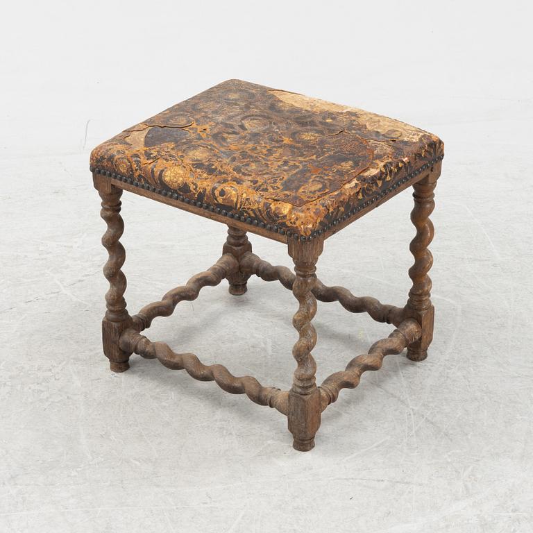 A turned oak Baroque style stool, 19thb Century, covered with older gilt leather.