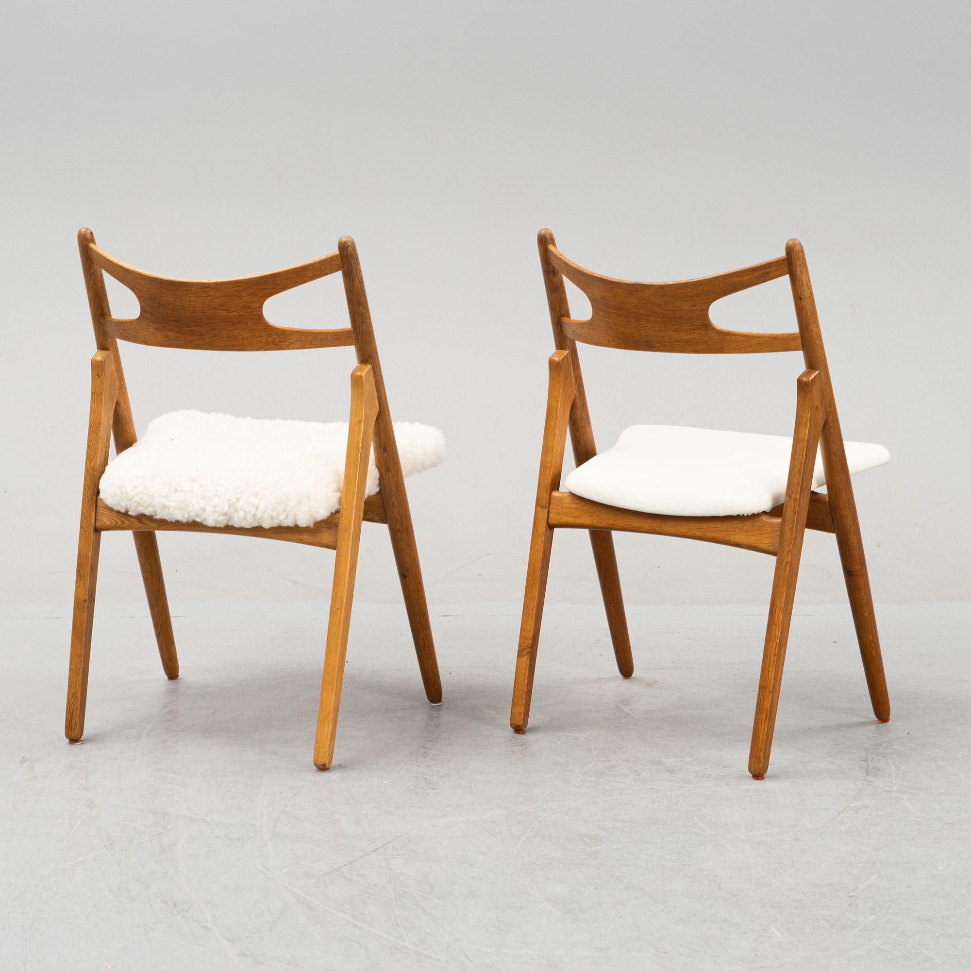 A set of six model CH 29 oak chairs by Hans J Wegner, two with leather upholstery and four with sheepskin.