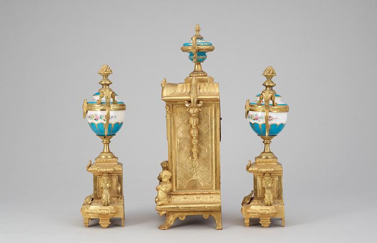 A Louis XVI style gilt bronze and porcelaine table clock and a pair of urns with covers.