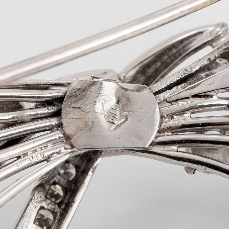 An 18K white gold brooch set with round brilliant- and eight-cut diamonds.