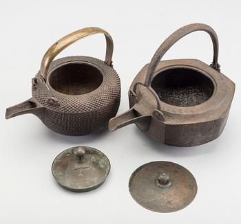 A set of two Japanese early 20th century cast iron chōshi (銚子).