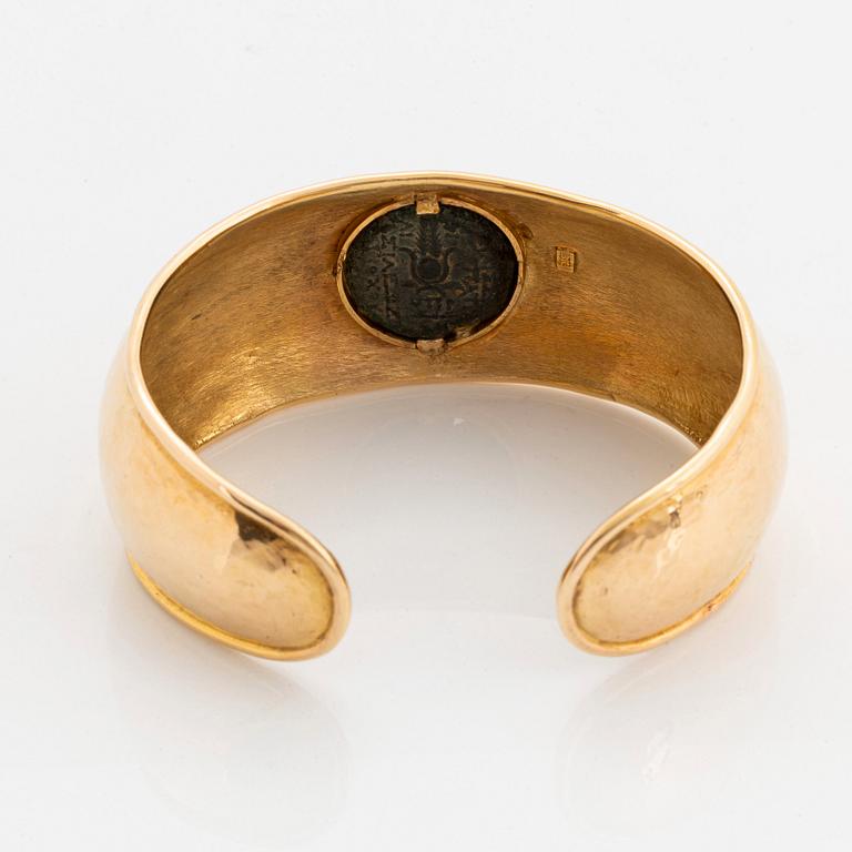 An 18K gold bangle set with an ancient coin.