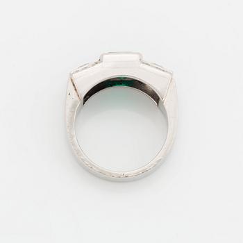 A platinum ring set with a step-cut emerald and round brilliant- and step-cut diamonds.