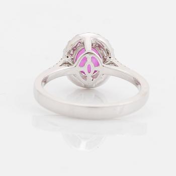 An 18K white gold ring set with a faceted pink sapphire and round brilliant-cut diamonds.