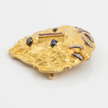 An 18K gold brooch set with diamonds and colored stones.