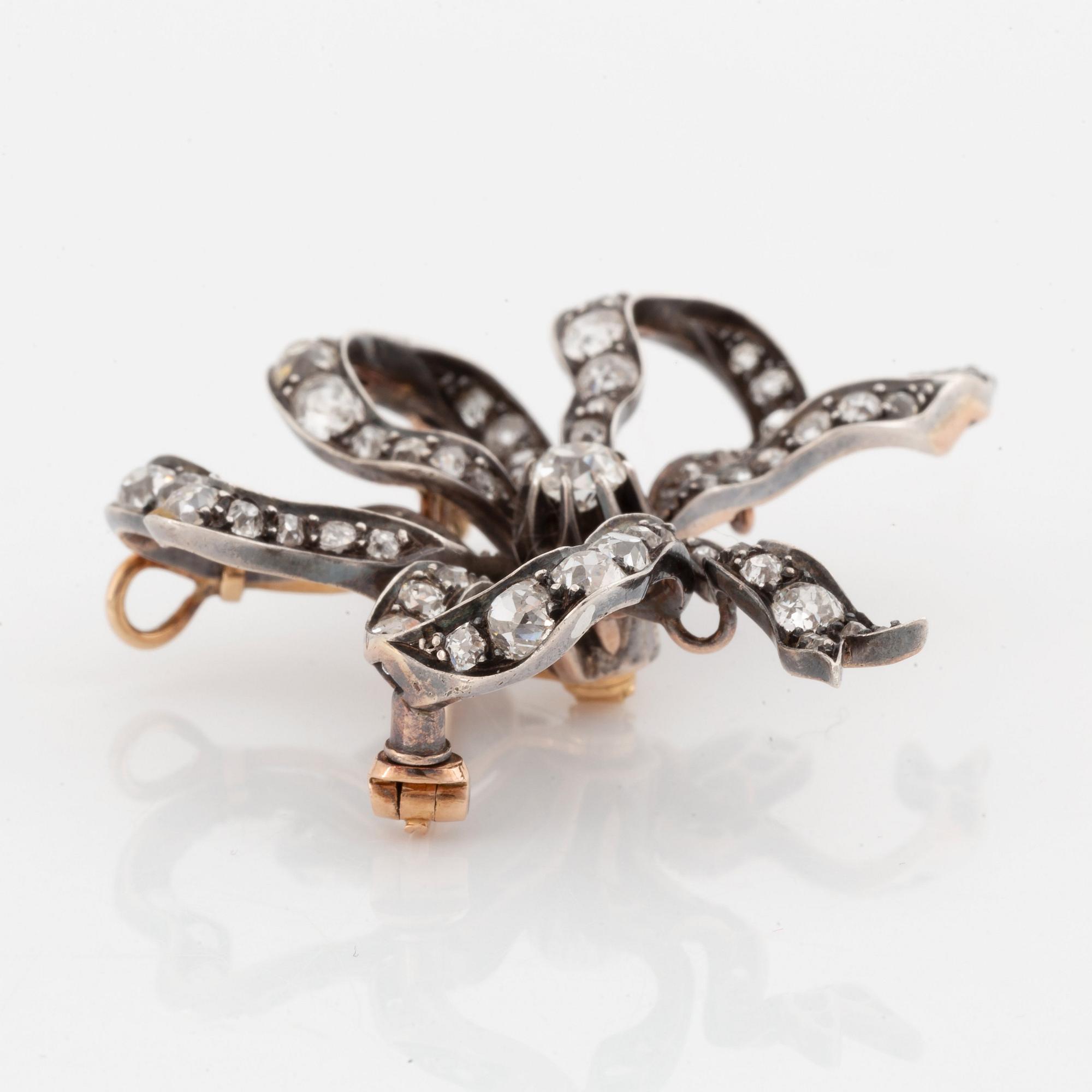 A silver and 14K gold bow brooch/pendant set with old- and rose-cut diamonds.