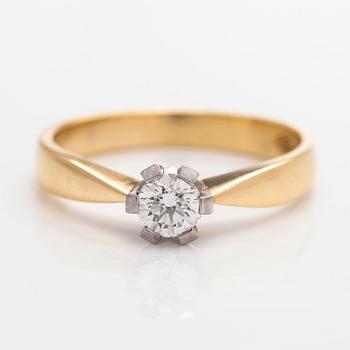 An 18K gold solitaire ring with a brilliant-cut diamond.