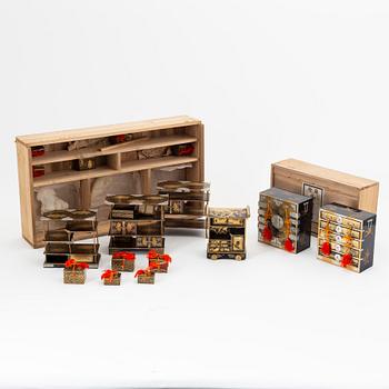 A group of Japanese lacquered miniature furniture and boxes in wooden crates, early 20th Century.