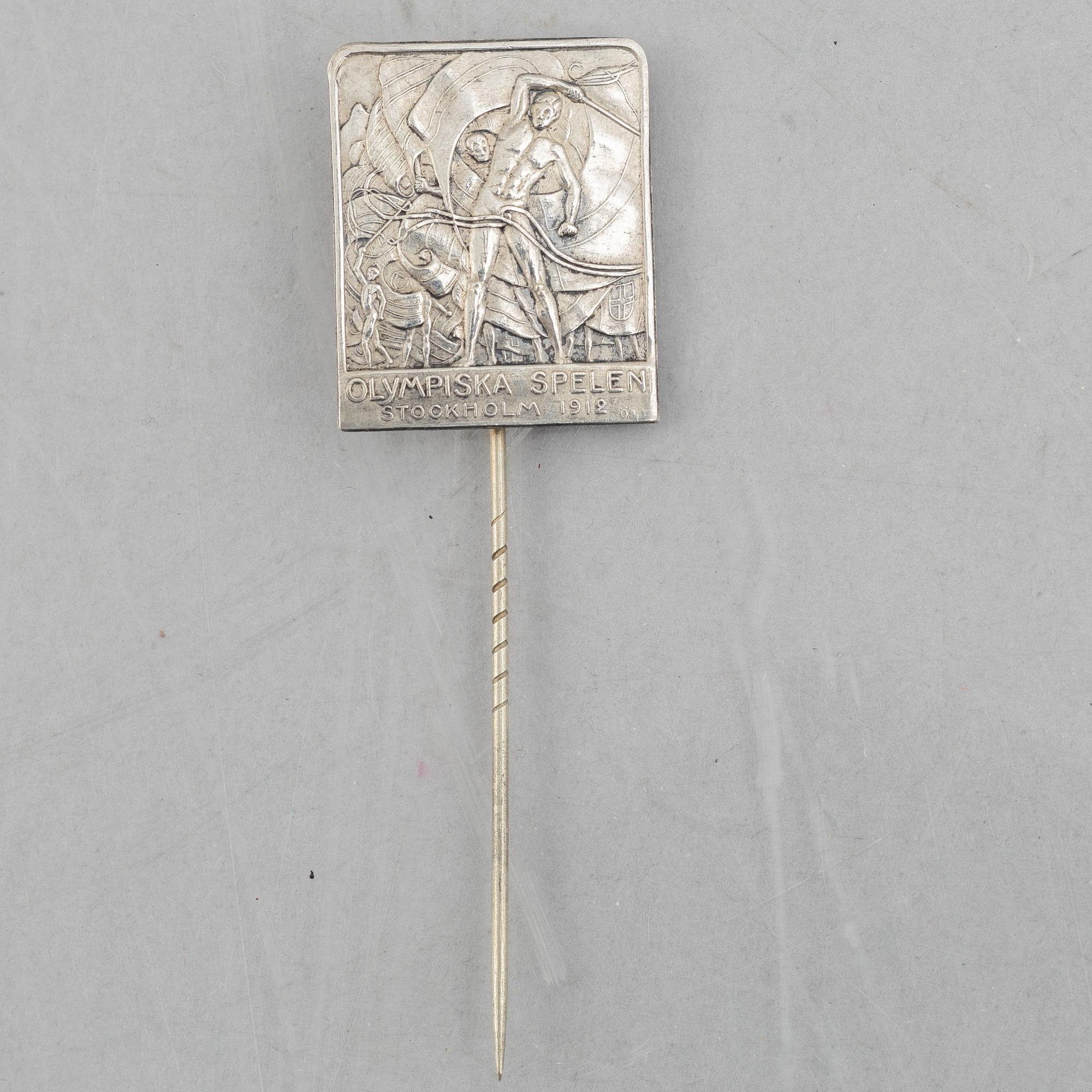 A pair of candlesticks and a commemorative pin from the Olympic Games in Stockholm 1912.