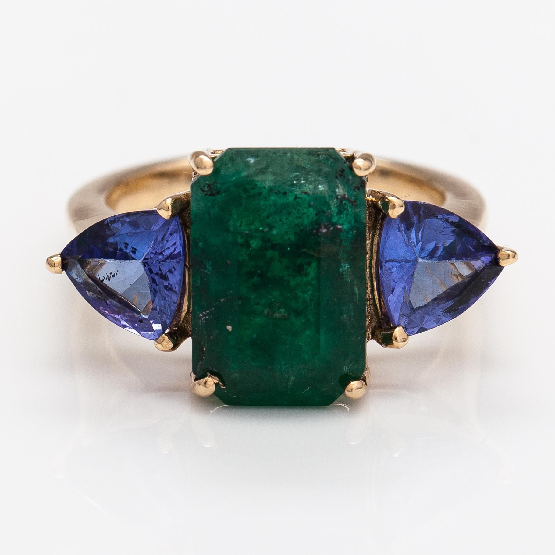 A 14K gold ring with tanzanites and a ca 5.80 ct emerald.