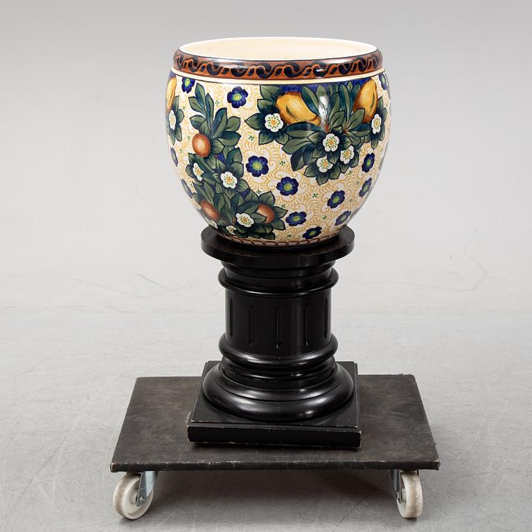A handpainted faience, urn on wooden pedestal. Aluminia, Denmark. Dated 1910.