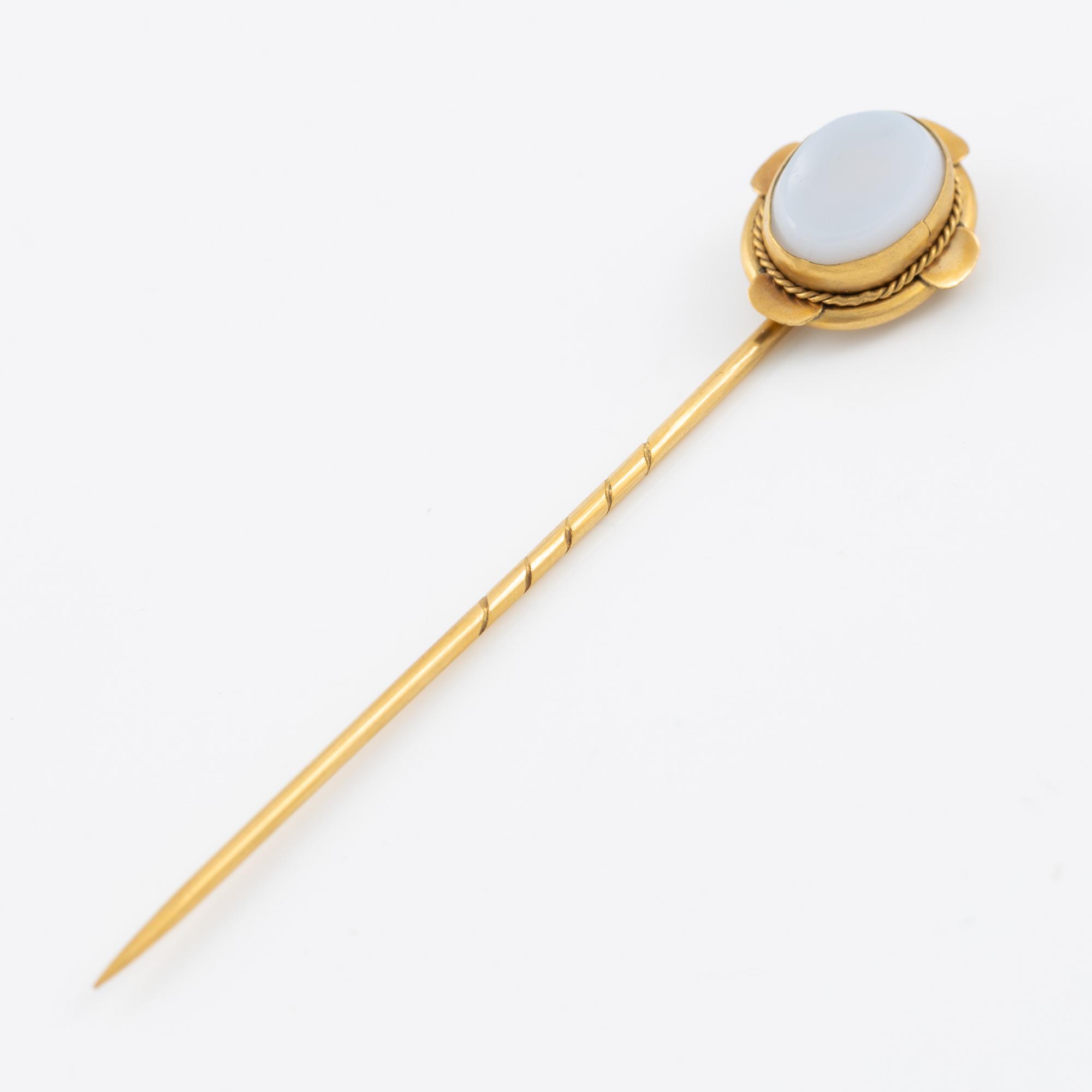 Brooch pin of low-grade gold with a white-blue stone.