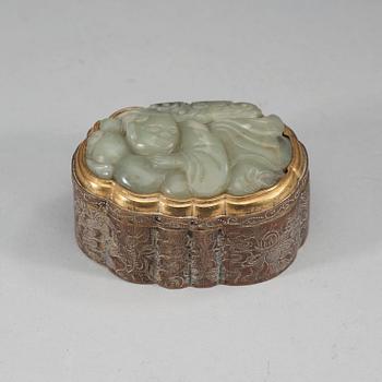 A partly gilded metal box with cover, mounted with a carved pale celadon nephrite plaque. Late Qing dynasty (1644-1912).