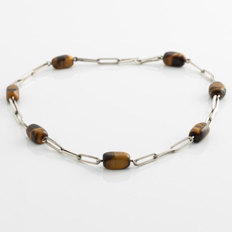Birger Haglund, a silver and tiger's eye necklace.