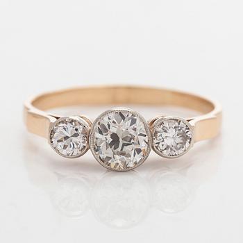 A 14K gold three-stone ring, set with an old-cut and brilliant-cut diamonds.