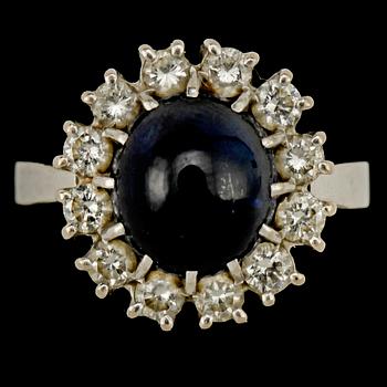 RING, 18k vitguld med blå cabochonslipad safir, 3.81 ct samt 12 briljantslipade diamanter, tot 0.77 ct. Vikt 6 g.