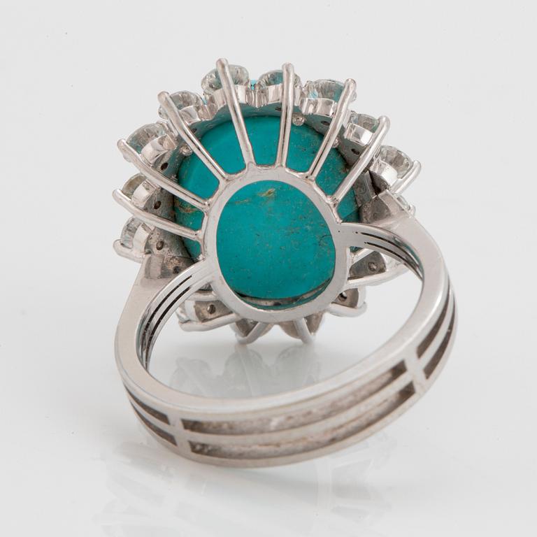 An 18K white gold ring set with a cabochon-cut turquoise and round brilliant-cut diamonds.