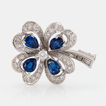 987. A Meister brooch in 18K white gold set with faceted sapphires, a round brilliant-cut diamond.