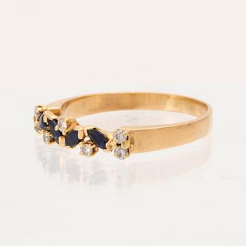 An 18K gold ring set with marquise cut, likely,  sapphires and round brilliant cut diamonds.