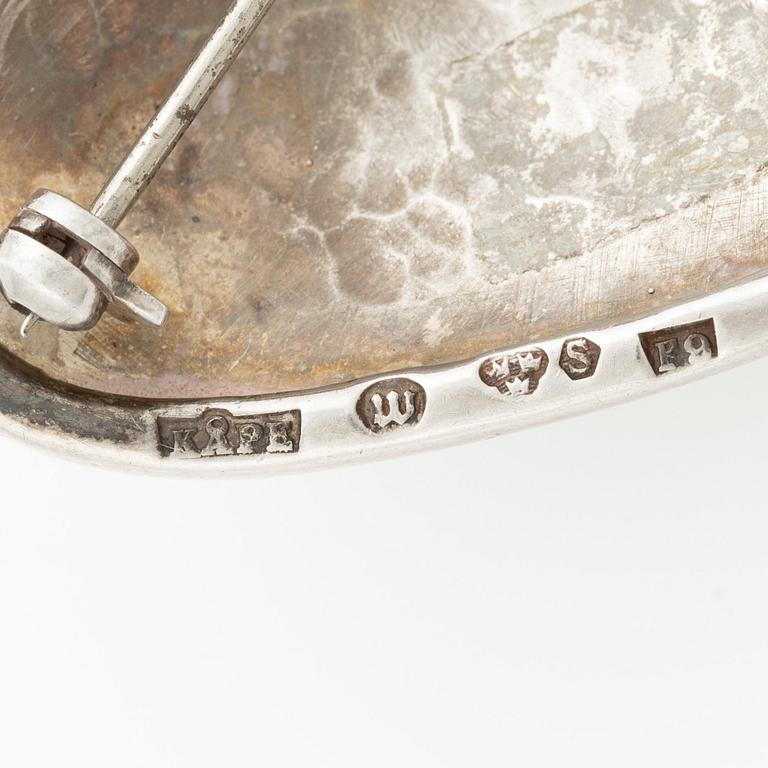 Två broscher, silver och stenar.