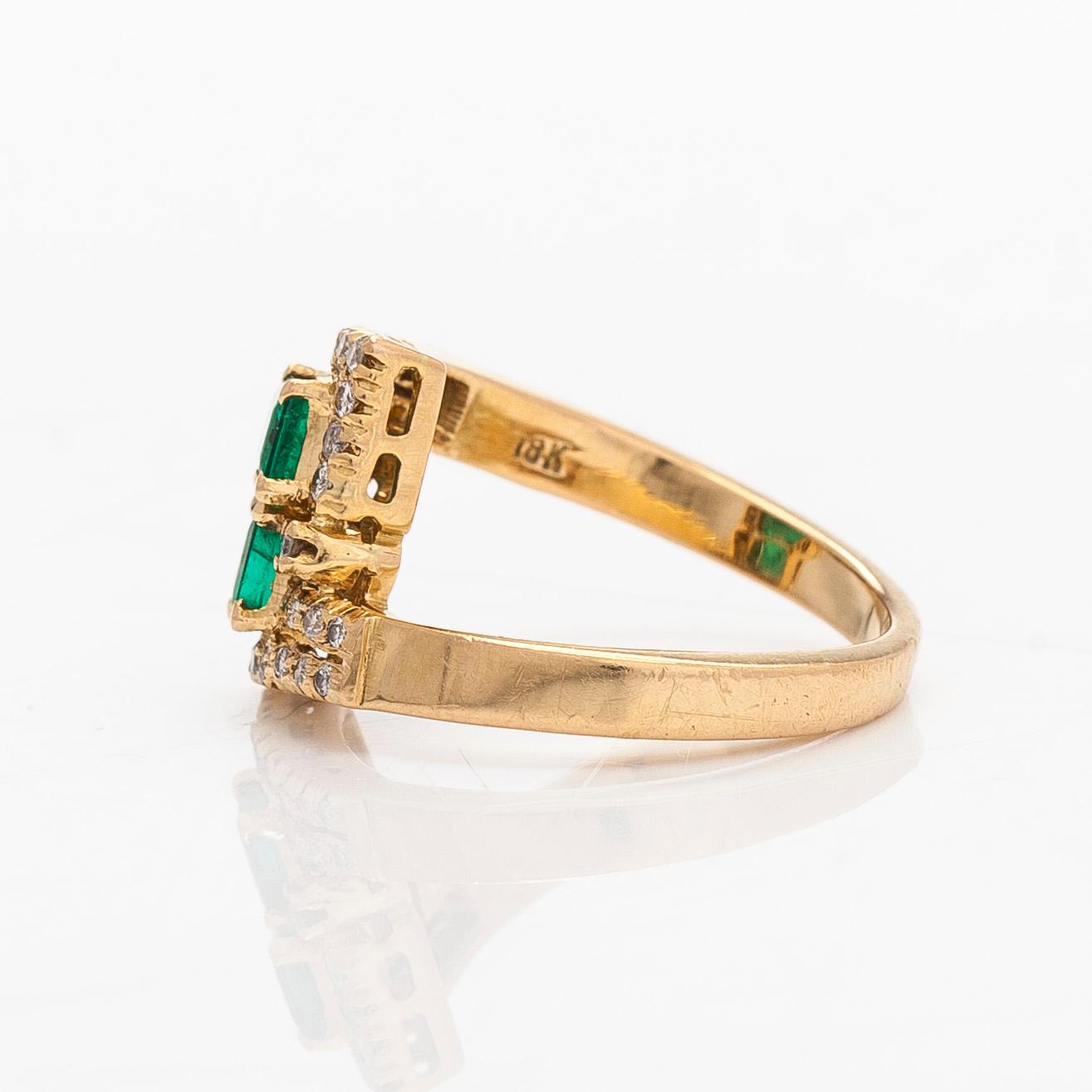 An 18K gold ring with emeralds and diamonds.